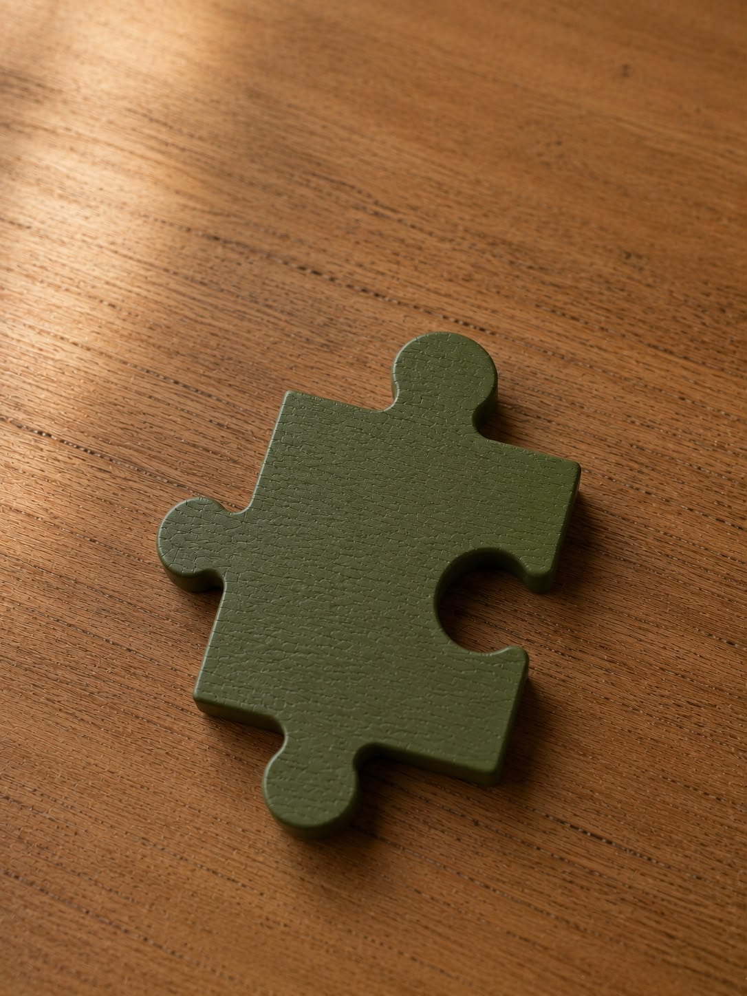 Ein einzelnes grünes Puzzleteil auf einem Holztisch